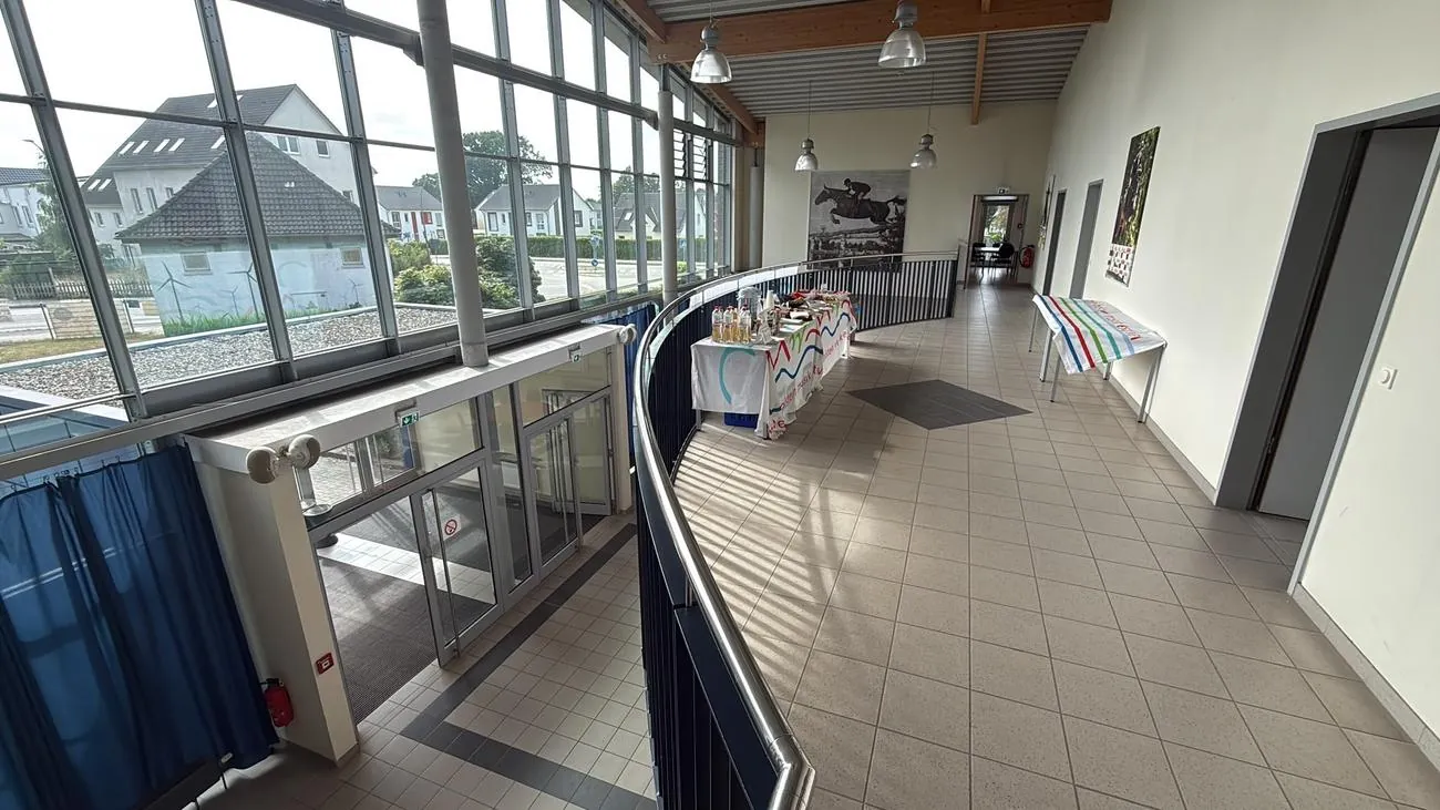 Helles Foyer mit hoher Glasfassade, Galerie mit Geländer und aufgebauten Empfangstischen