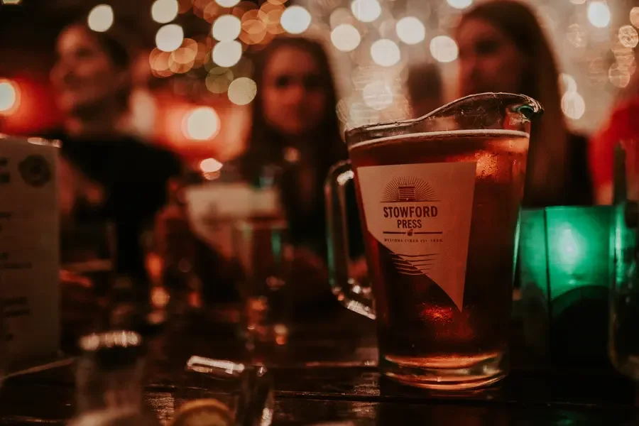 Feierabend im Broderick Irish Pub Elmshorn: Cider-Krug auf dem Tisch, Gäste und Lichterketten im warmen Licht